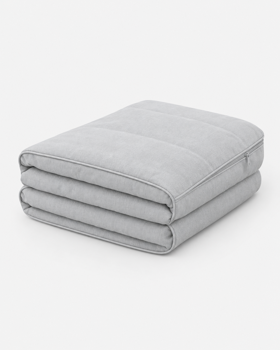 A washable dog bed cover in very light cool grey, folded into a neat stack on a plain light grey background.