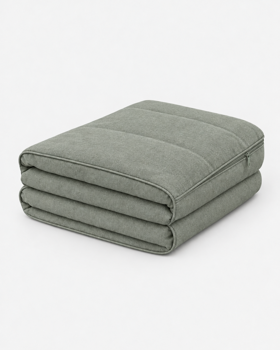 A washable dog bed cover in soft grey-green, folded into a neat stack on a plain light grey background.