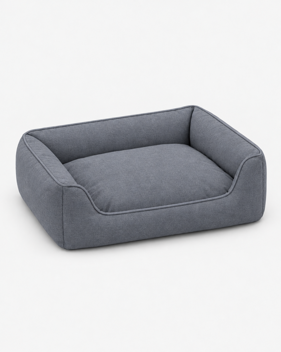 The same low bolster dog bed in a mid cool grey woven fabric on a plain light grey studio background.