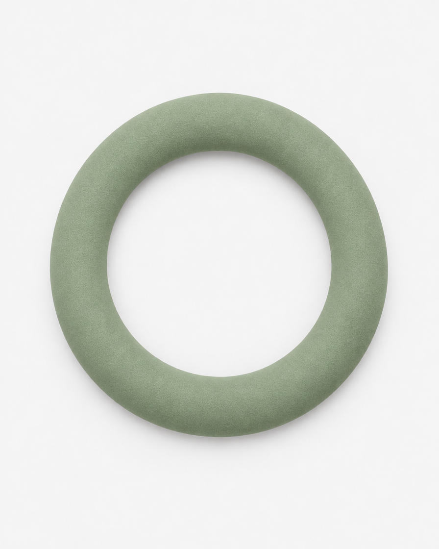 A soft grey-green flying ring dog toy seen from above on a light grey background.