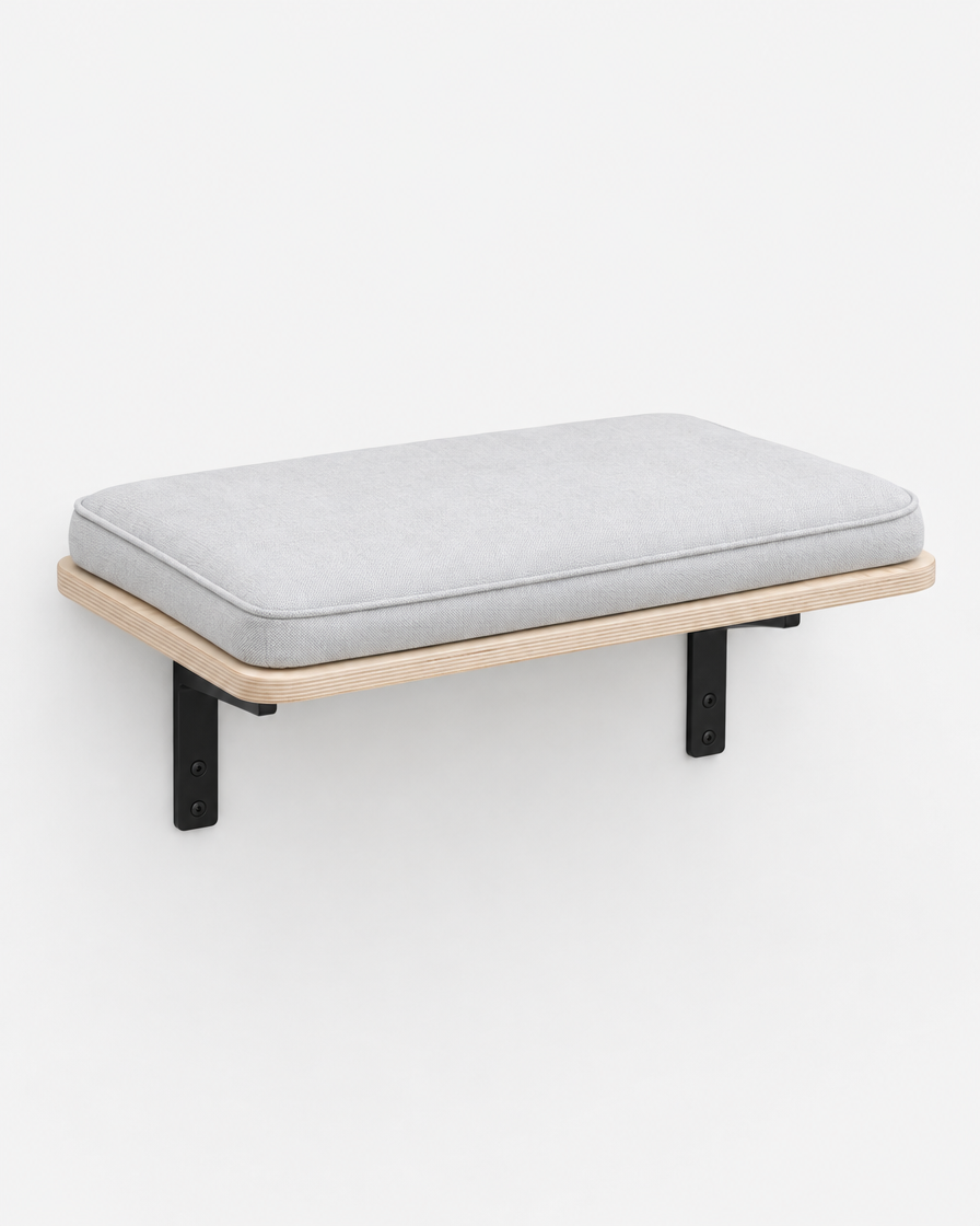 A wall-mounted birch plywood cat perch with two black brackets and a light grey cushion, photographed on a plain light grey background.