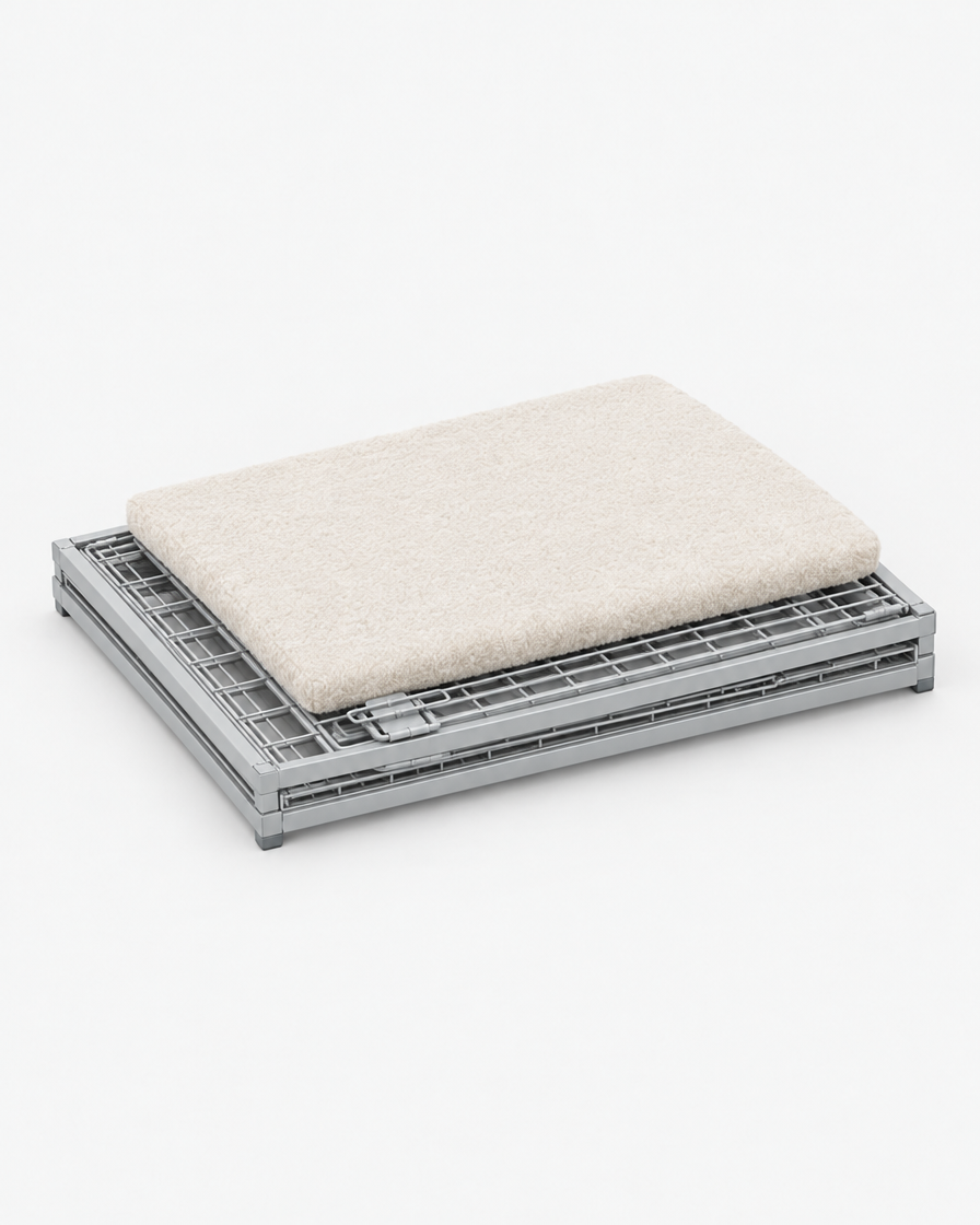 The light grey steel wire dog crate folded flat into a slim panel with its cream cushion pad resting on top.