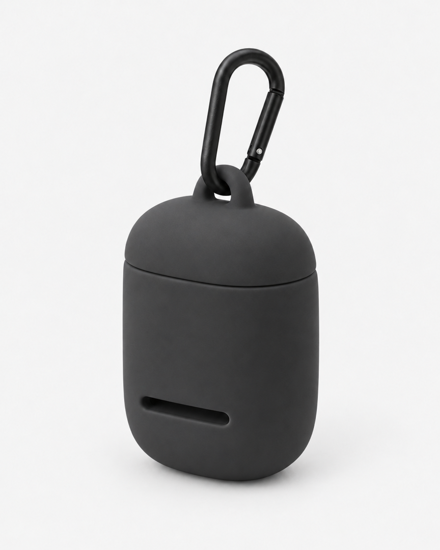 A small rounded silicone waste-bag pouch in near-black warm grey with a magnetic lid, a front dispensing slot and a matte black carabiner, on a plain light grey background.