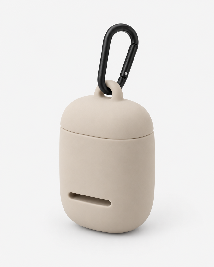 A small rounded silicone waste-bag pouch in warm beige with a magnetic lid, a front dispensing slot and a matte black carabiner, on a plain light grey background.