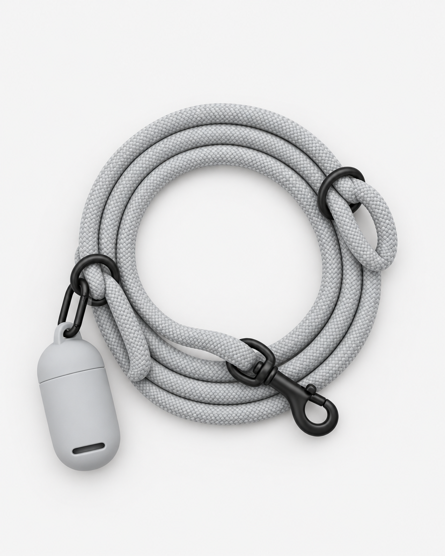 Top-down studio photo of a light grey rope leash coiled neatly with a small grey silicone waste-bag pouch clipped to one of its black rings.